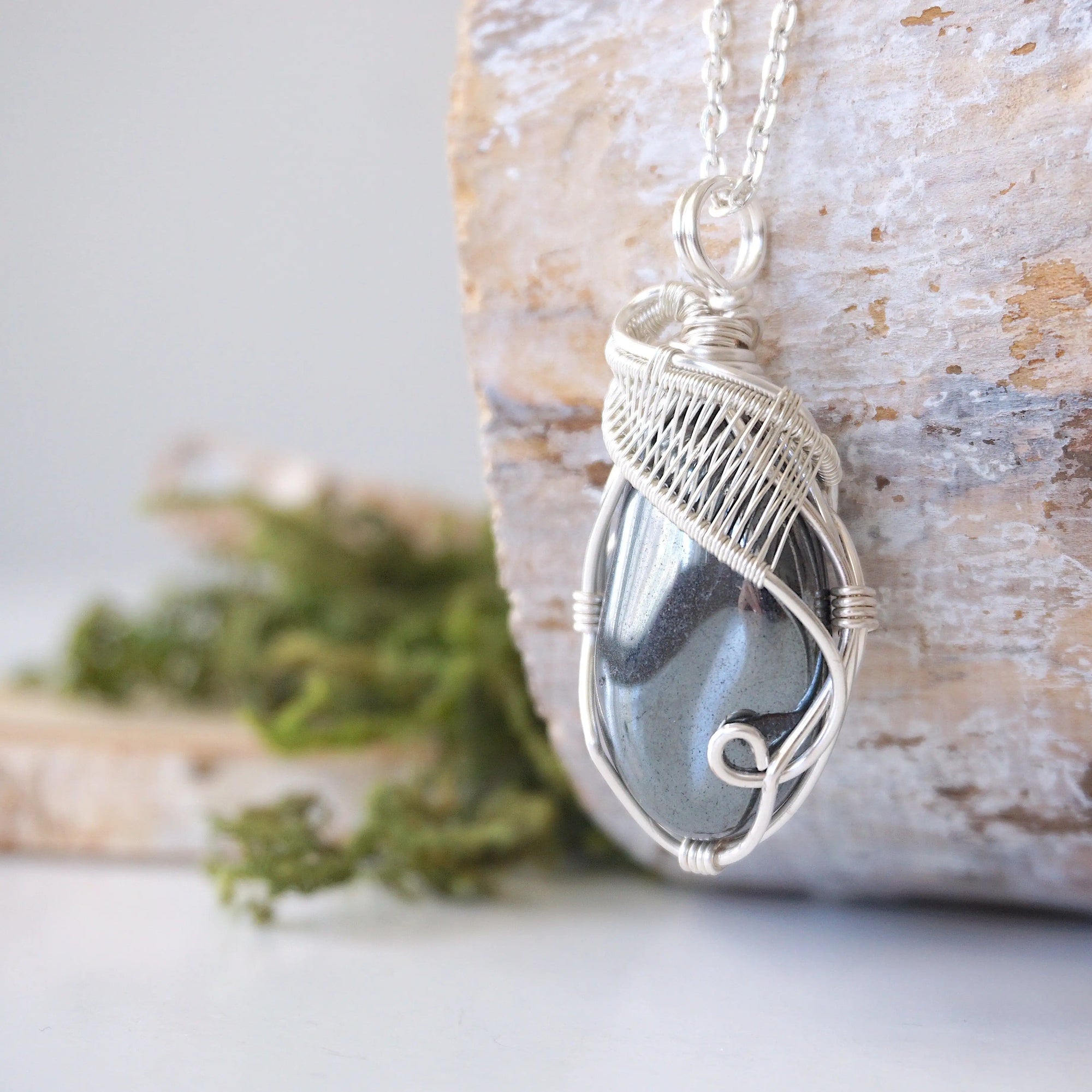 Left angle close-up of natural hematite pendant highlighting detailed soft silver over copper wire wrapping