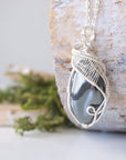 Left angle close-up of natural hematite pendant highlighting detailed soft silver over copper wire wrapping