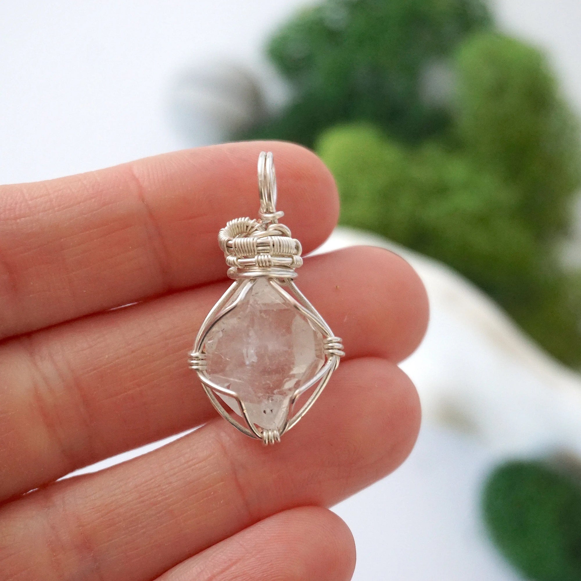 Raw Herkimer diamond pendant shown in hand for size reference, handmade in soft silver copper wire.