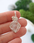 Raw Herkimer diamond pendant shown in hand for size reference, handmade in soft silver copper wire.