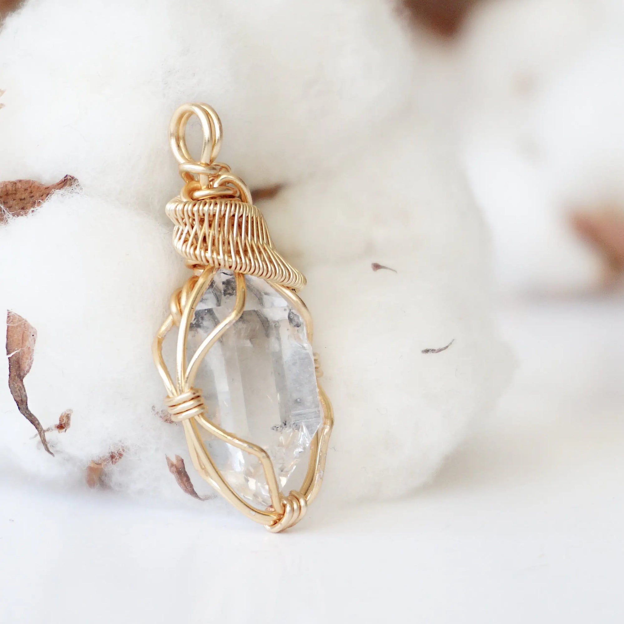 Right angle view of raw Herkimer diamond pendant showing detailed artisan wire wrapping in warm gold copper.