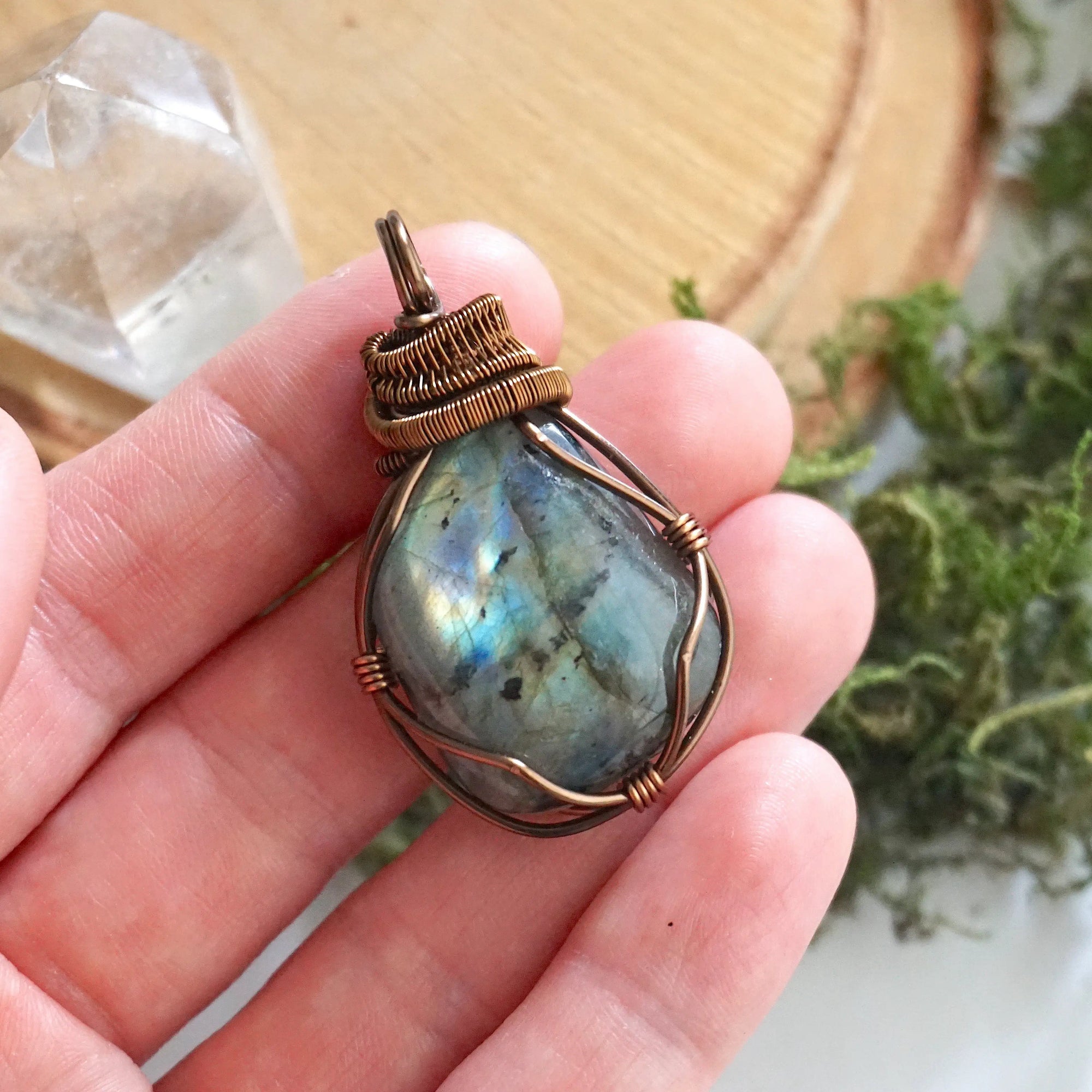 Labradorite pendant held in hand showing stone size — 80 to 100 carat polished-raw labradorite in antique bronze wire wrap