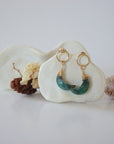 Front angle look at Lux Emerald Moon Open Circle Stud Earrings on jewelry display, faceted natural emerald, gold filled, handmade.