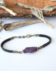 Full view of men’s amethyst bracelet with raw amethyst stone wrapped in antique bronze copper on black leather cord