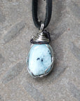 Back angle of men's aquamarine pendant on a black leather cord, highlighting wire wrapped setting and natural stone texture, black and white gold finish