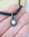 Men’s pearl pendant necklace shown in hand for size reference, featuring an antiqued sterling silver wrapped pearl