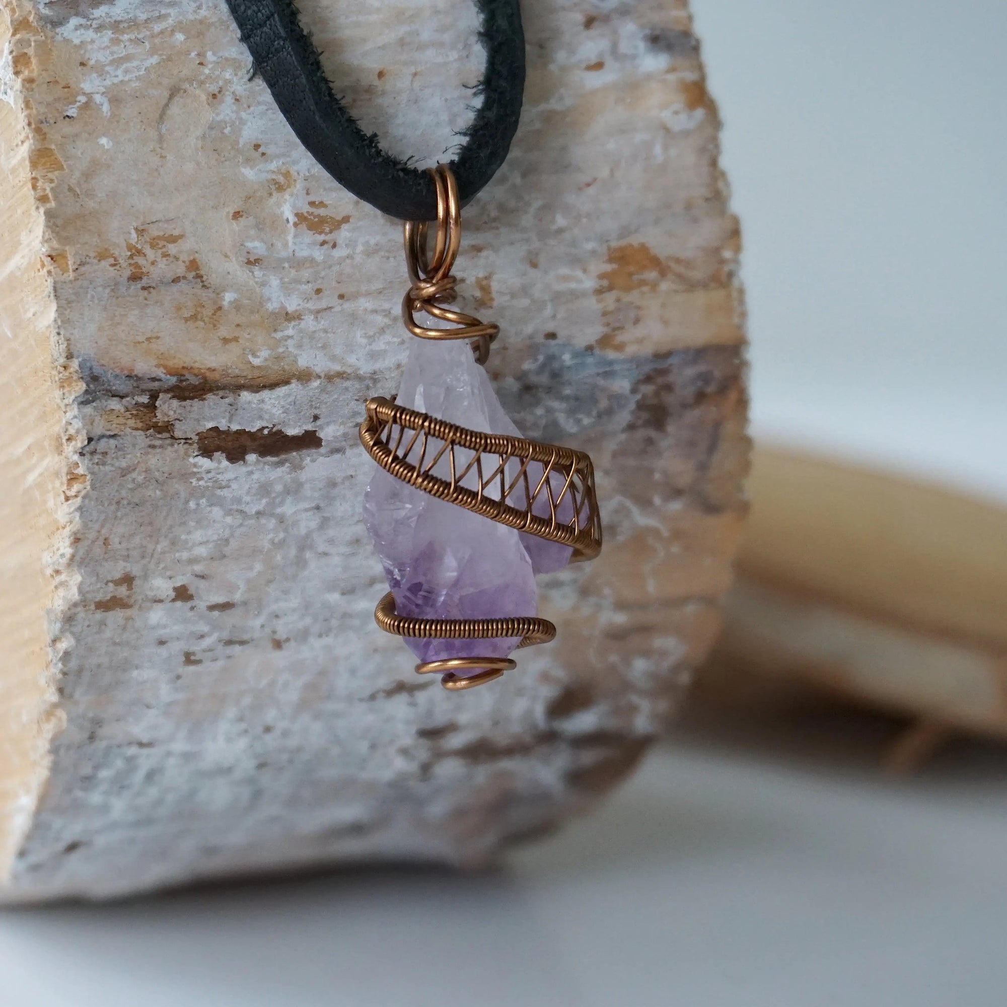 Right side view of raw amethyst crystal pendant wire wrapped in antique bronze copper on black leather cord, men’s necklace