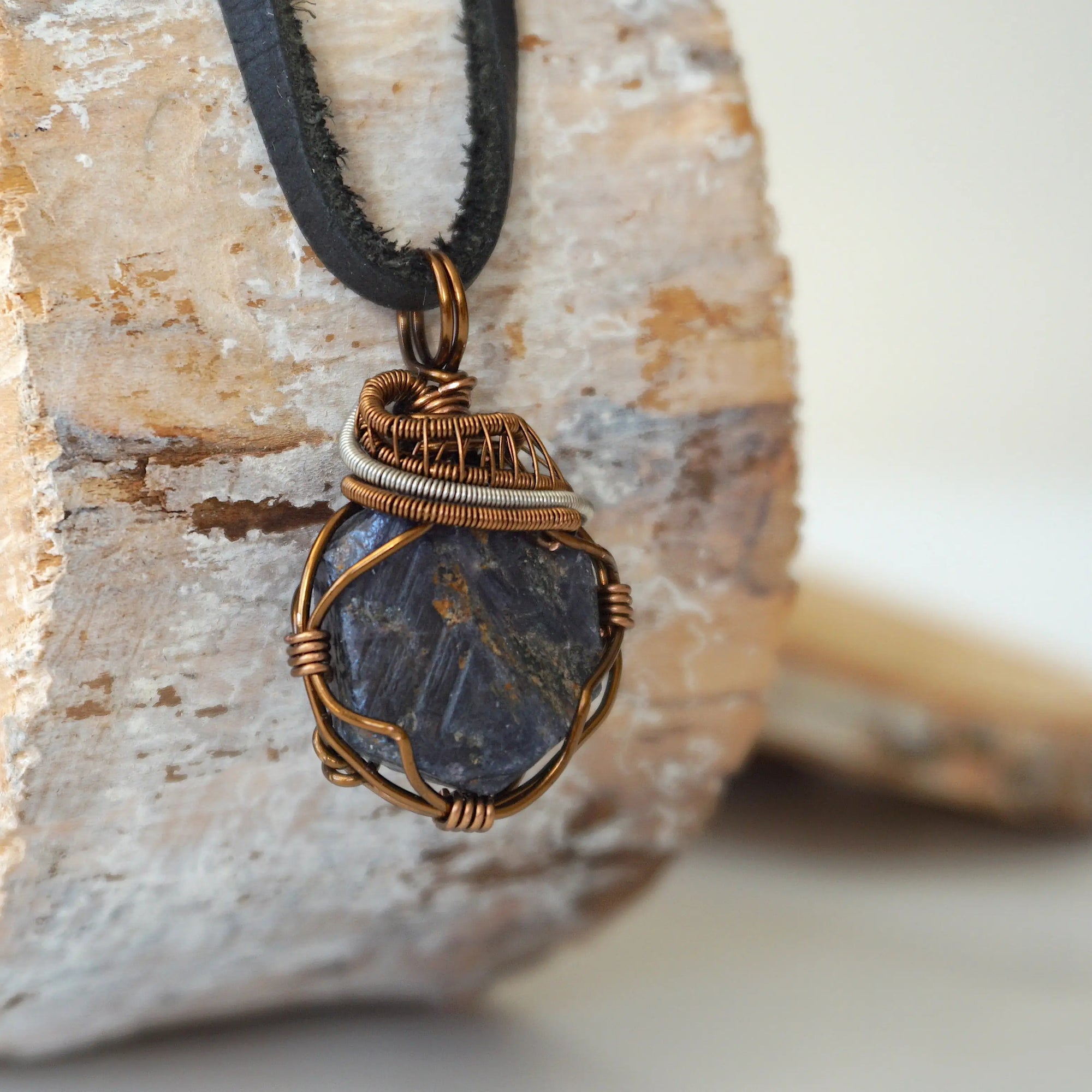 Right-angle detail of men's raw sapphire pendant showing artisan wire-wrapping in antique bronze and dark silver — handcrafted crystal necklace