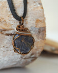 Right-angle detail of men's raw sapphire pendant showing artisan wire-wrapping in antique bronze and dark silver — handcrafted crystal necklace