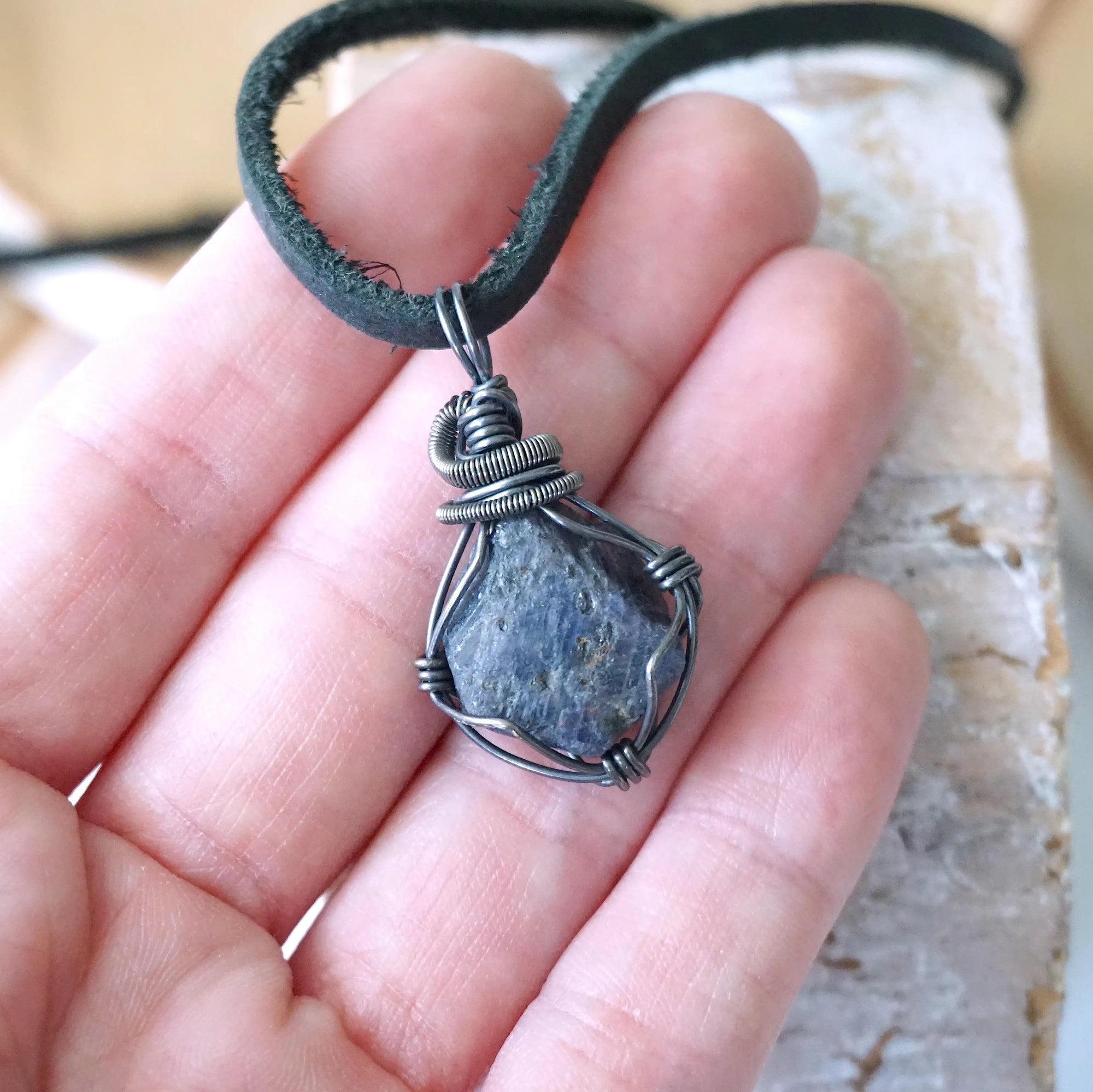 Raw sapphire pendant held in hand to show size — antiqued 925 sterling silver wire wrap, men's handcrafted crystal necklace by Designs by Nature Gems