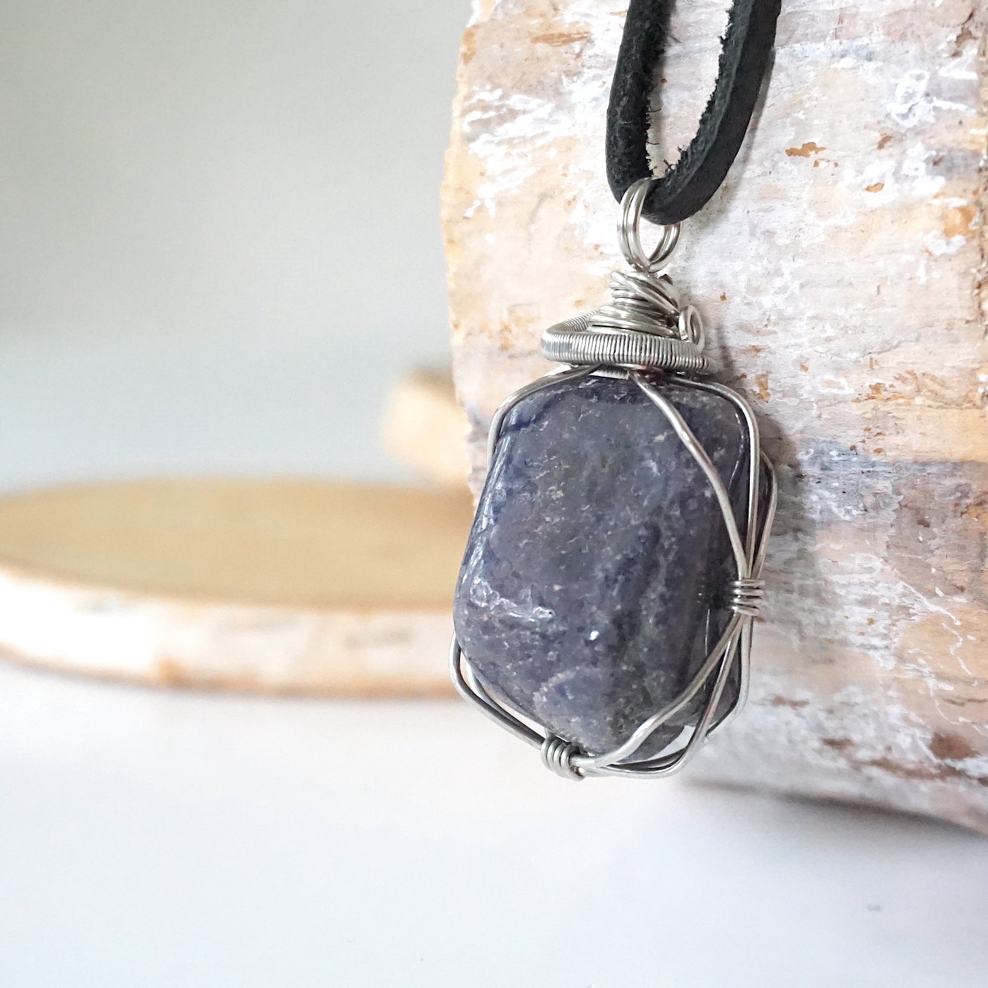 Left-angle close-up of natural sapphire pendant revealing the precision of dark silver wire-wrapping craftsmanship — men's artisan crystal jewelry