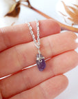 Minimalist amethyst necklace for women shown in hand for size reference, silver plated copper wire wrap