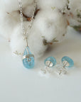 Front angle view of aquamarine necklace and back side of earrings, soft silver wire wrapped pendant and sterling silver stud earrings, March birthstone
