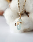 Left side angle of minimalist aquamarine necklace, polished aquamarine pendant, warm gold wire wrapping