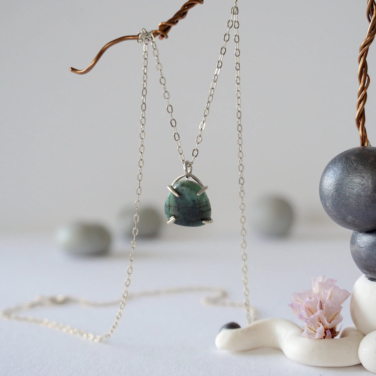 Front view of minimalist emerald necklace in 925 sterling silver with natural polished-raw emerald pendant for women.