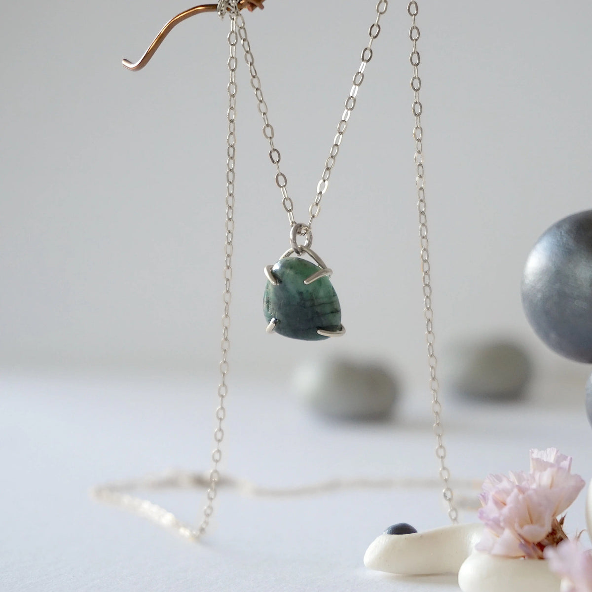 Side angle view of minimalist emerald necklace showing 925 sterling silver prong setting and natural raw emerald.