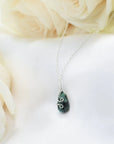 Detailed angle view of minimalist emerald necklace for women with faceted emerald and sterling silver wire wrapping