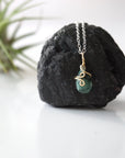 Zoomed out view of minimalist emerald necklace for women with faceted teardrop emerald on sterling silver chain