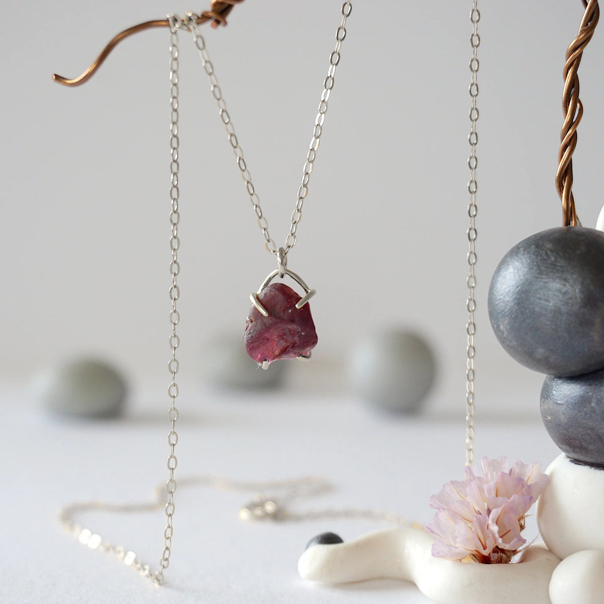 Close front view of minimalist raw garnet pendant in sterling silver claw setting on a sterling silver chain
