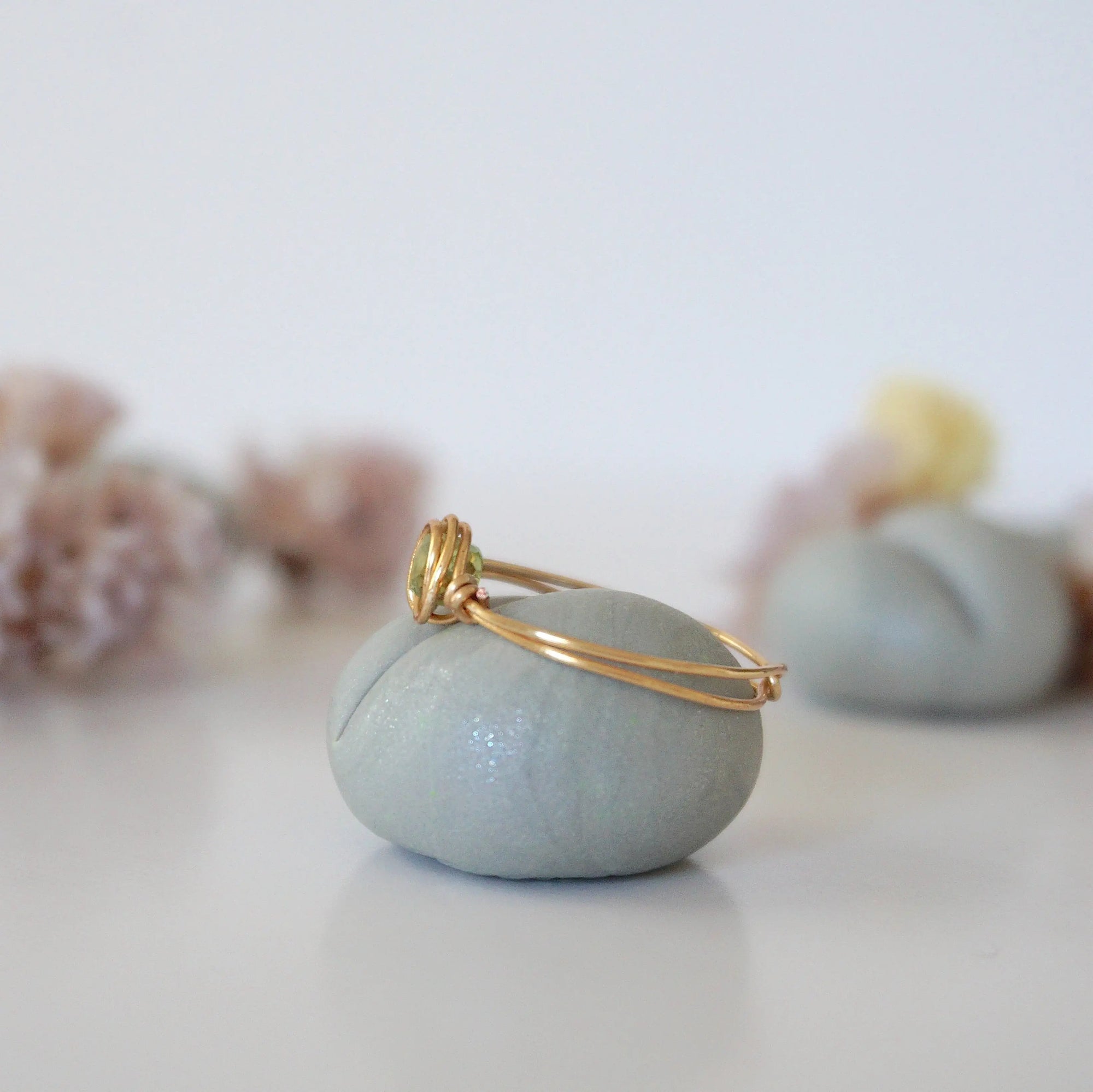 Side angle of minimalist gold wire wrapped peridot ring — artisan wire band and stone cradle detail in warm gold finish, dainty August birthstone ring for women