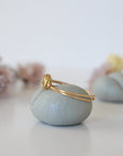 Side angle of minimalist gold wire wrapped peridot ring — artisan wire band and stone cradle detail in warm gold finish, dainty August birthstone ring for women