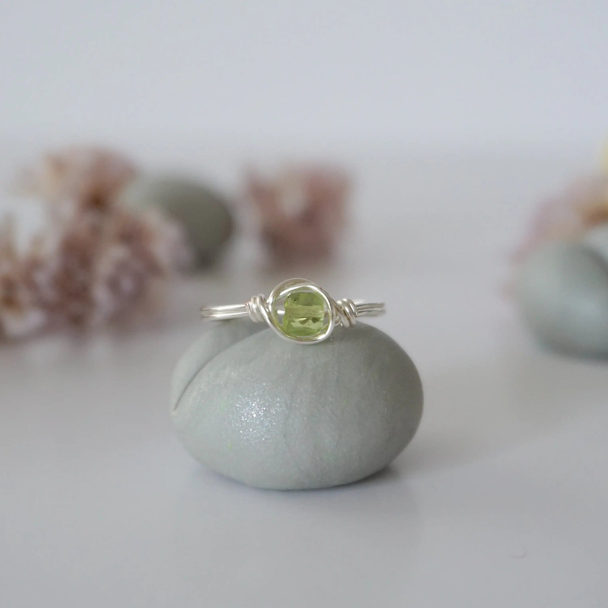 Front view of minimalist silver wire wrapped peridot ring — faceted 5mm olive green peridot bead, dainty handcrafted August birthstone crystal ring for women