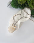 Handmade silver wire wrapped moonstone and freshwater pearl necklace laying flat on a silver plated chain, artisan jewelry for women