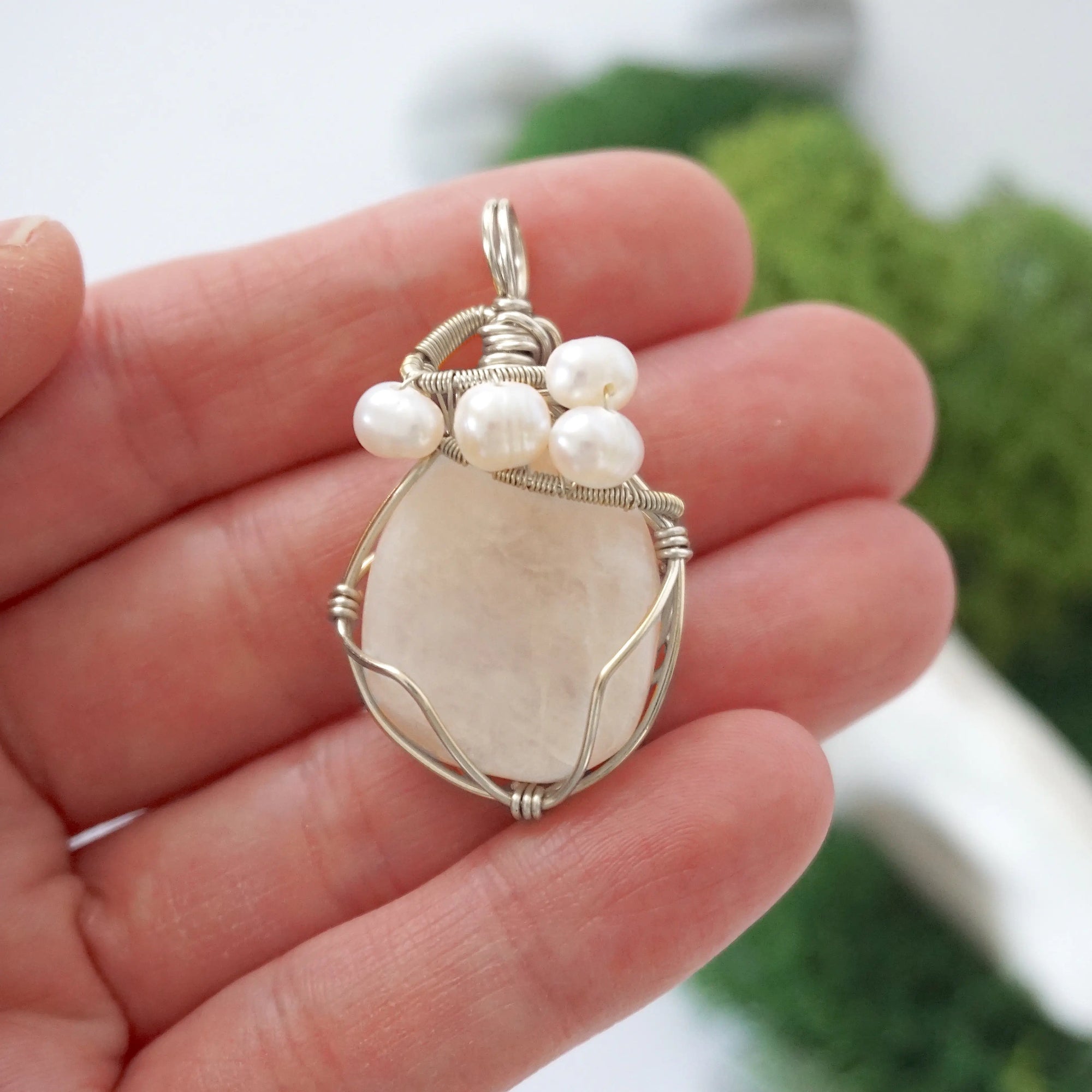 Moonstone and freshwater pearl pendant necklace in hand for size reference, silver wire wrapped, handcrafted gemstone jewelry