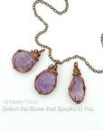 Three natural amethyst wire wrapped pendants on antique bronze chain showing stone color and shape variation