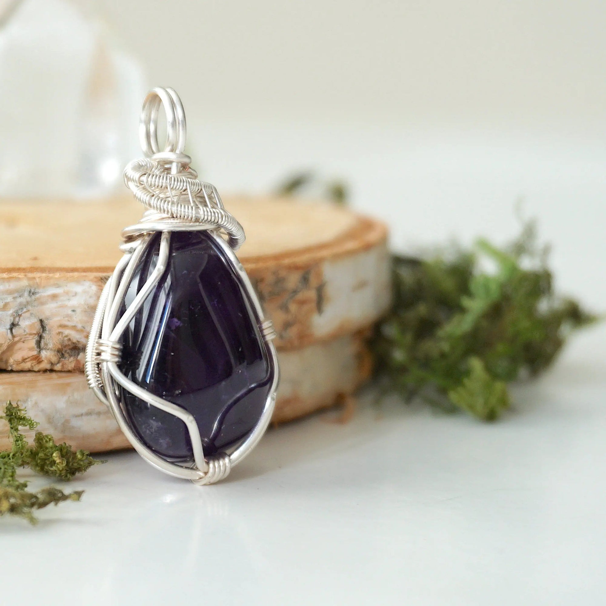 Right side view detail of polished dark amethyst pendant with silver plated copper wire wrapping, handmade necklace