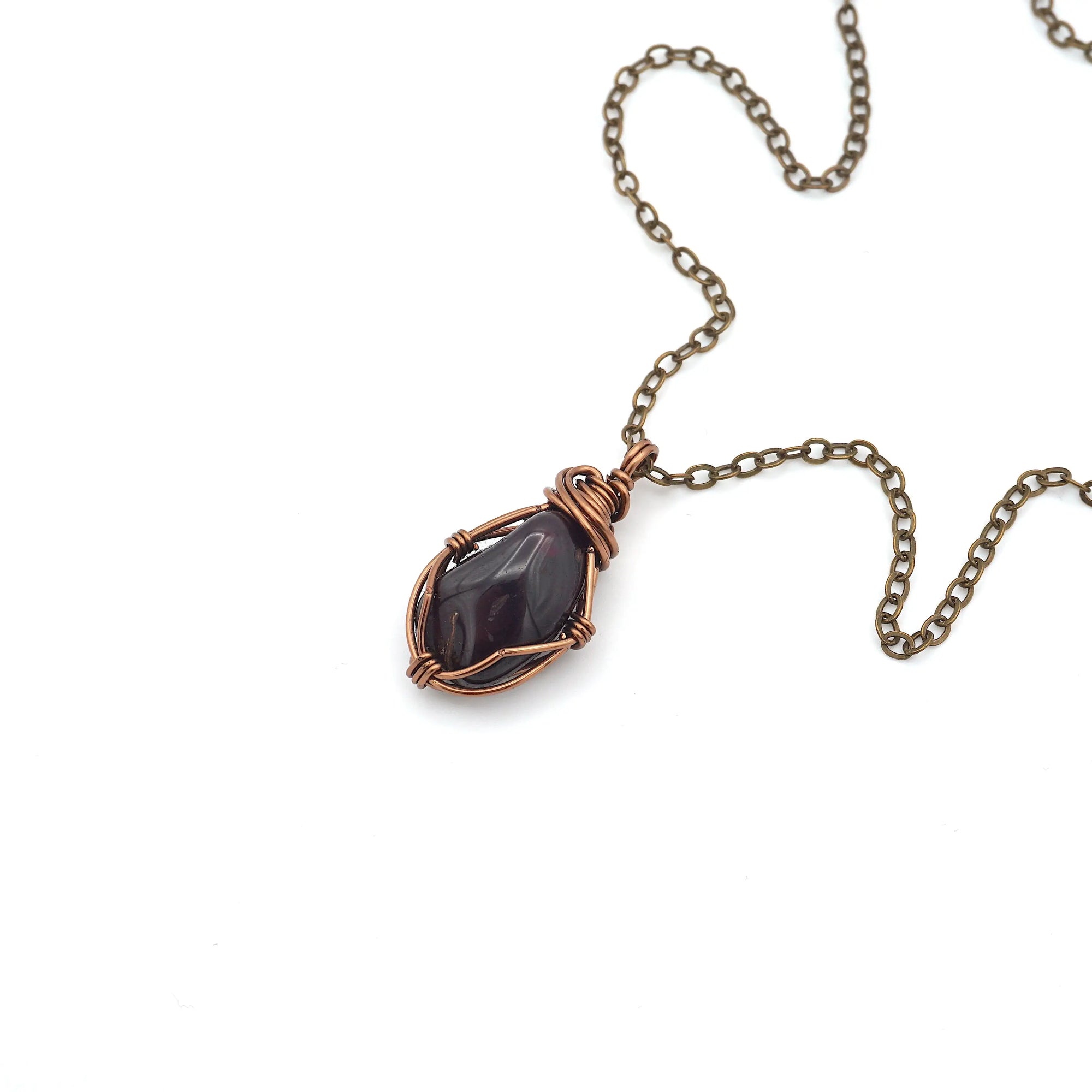 Natural garnet necklace with raw crystal pendant on antique bronze copper chain laying flat