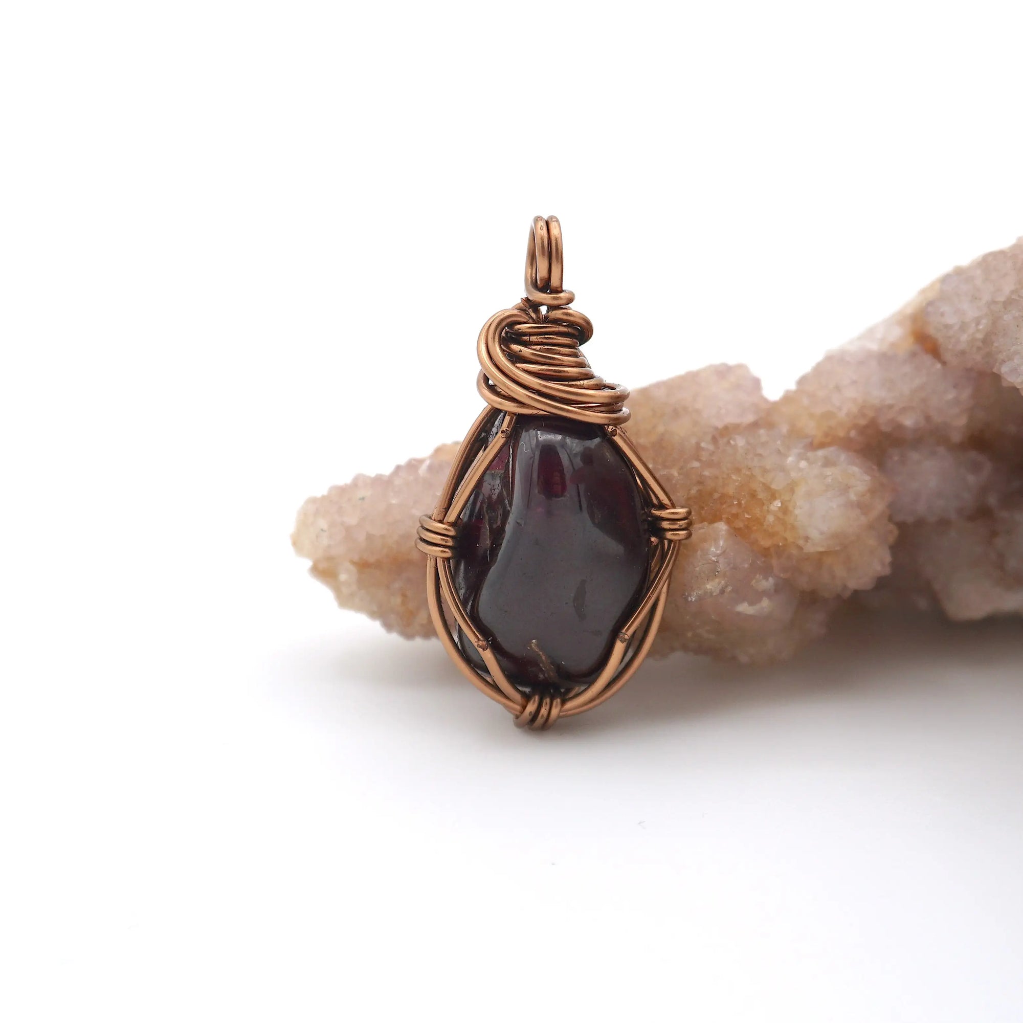 Detailed front angle of handmade raw garnet crystal pendant wire wrapped in antique bronze copper