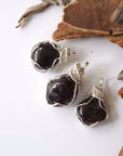Three natural raw garnet pendants showing variation in size, shape, and deep red color tones