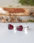Side view of natural raw garnet stud earrings showing raw stone texture and sterling silver post setting