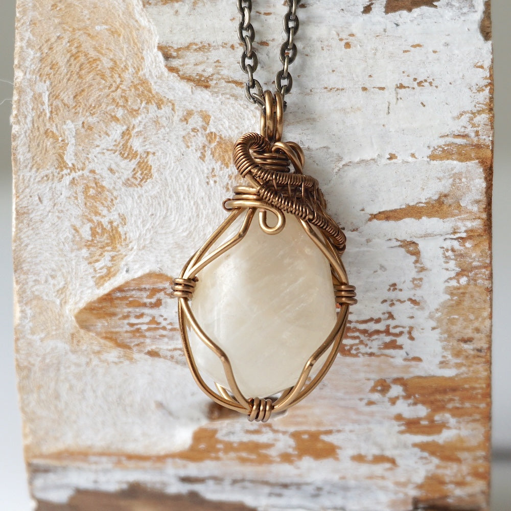 Close-up of natural polished-raw moonstone necklace, hand wire wrapped in antique bronze finish over copper (June birthstone).