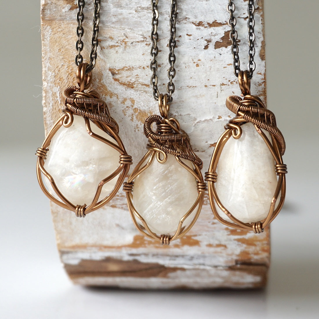 Three natural moonstone necklaces showing natural variation in pendant size, shape, and creamy moonstone color (June birthstone).