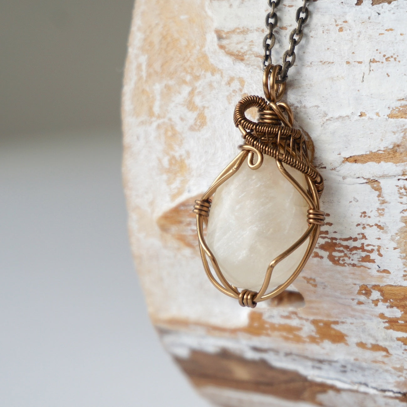 Left angle close-up of natural moonstone pendant necklace, antique bronze wire wrapped setting showing handcrafted detail.