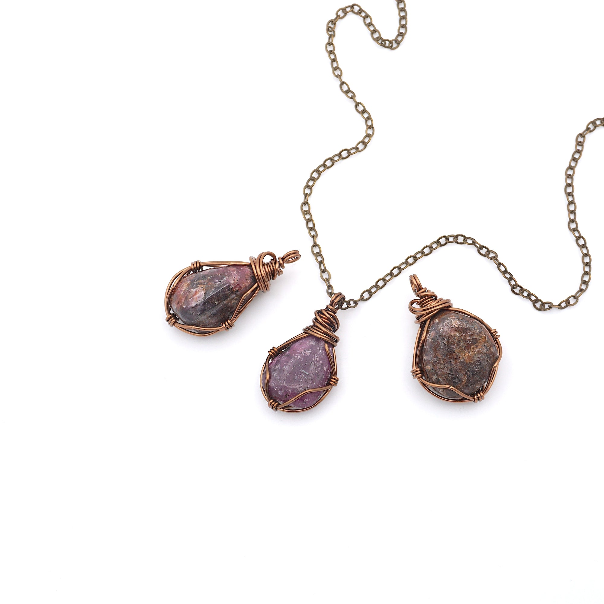Three natural raw ruby pendants side by side showing unique variation in size, shape, and colour — each one of a kind by nature