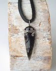 Detailed front view of men’s black obsidian arrowhead necklace on black leather cord, handcrafted crystal pendant by Designs by Nature Gems.