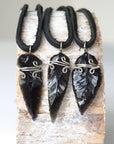 Three men’s black obsidian arrowhead pendants on black leather cords, showing natural crystal variations, artisan jewelry by Designs by Nature Gems.