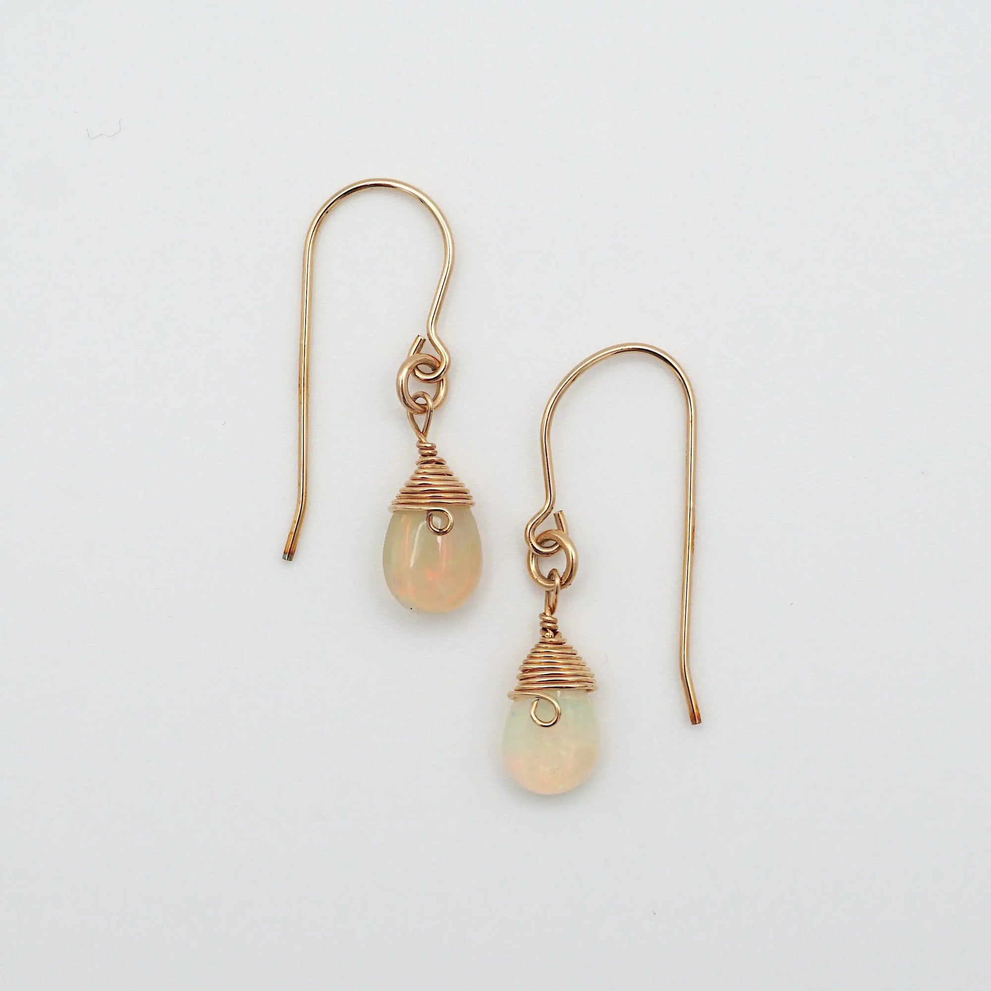 Detailed front view of opal drop earrings, natural faceted opal with minimalist 14k gold filled wire wrapping, Designs by Nature Gems