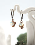 Close-up of handcrafted opal drop earrings with antique bronze copper wire wrapping.