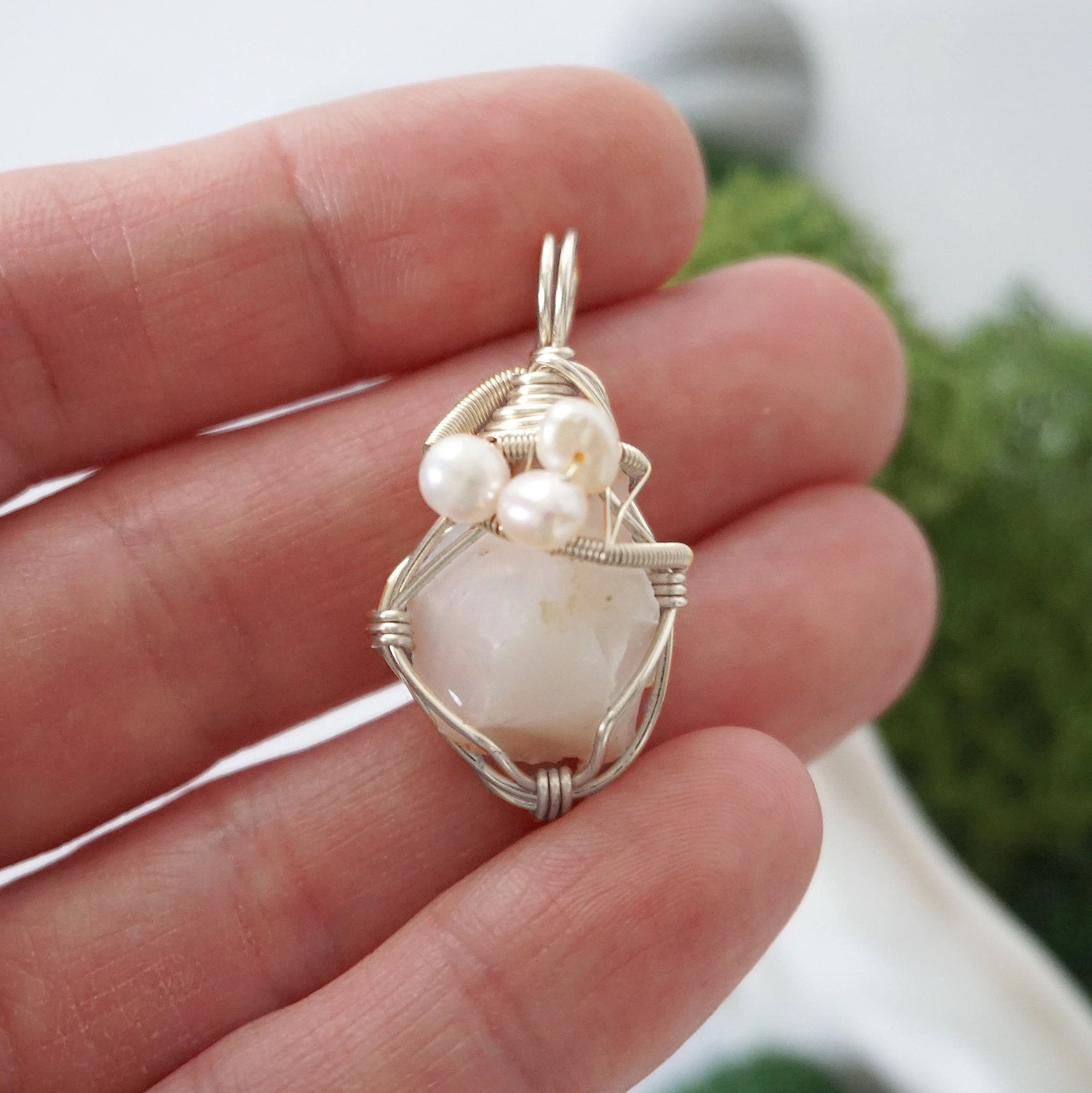 Opal and freshwater pearl pendant necklace in hand for size reference, silver wire wrapped, handcrafted gemstone jewelry