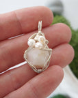 Opal and freshwater pearl pendant necklace in hand for size reference, silver wire wrapped, handcrafted gemstone jewelry