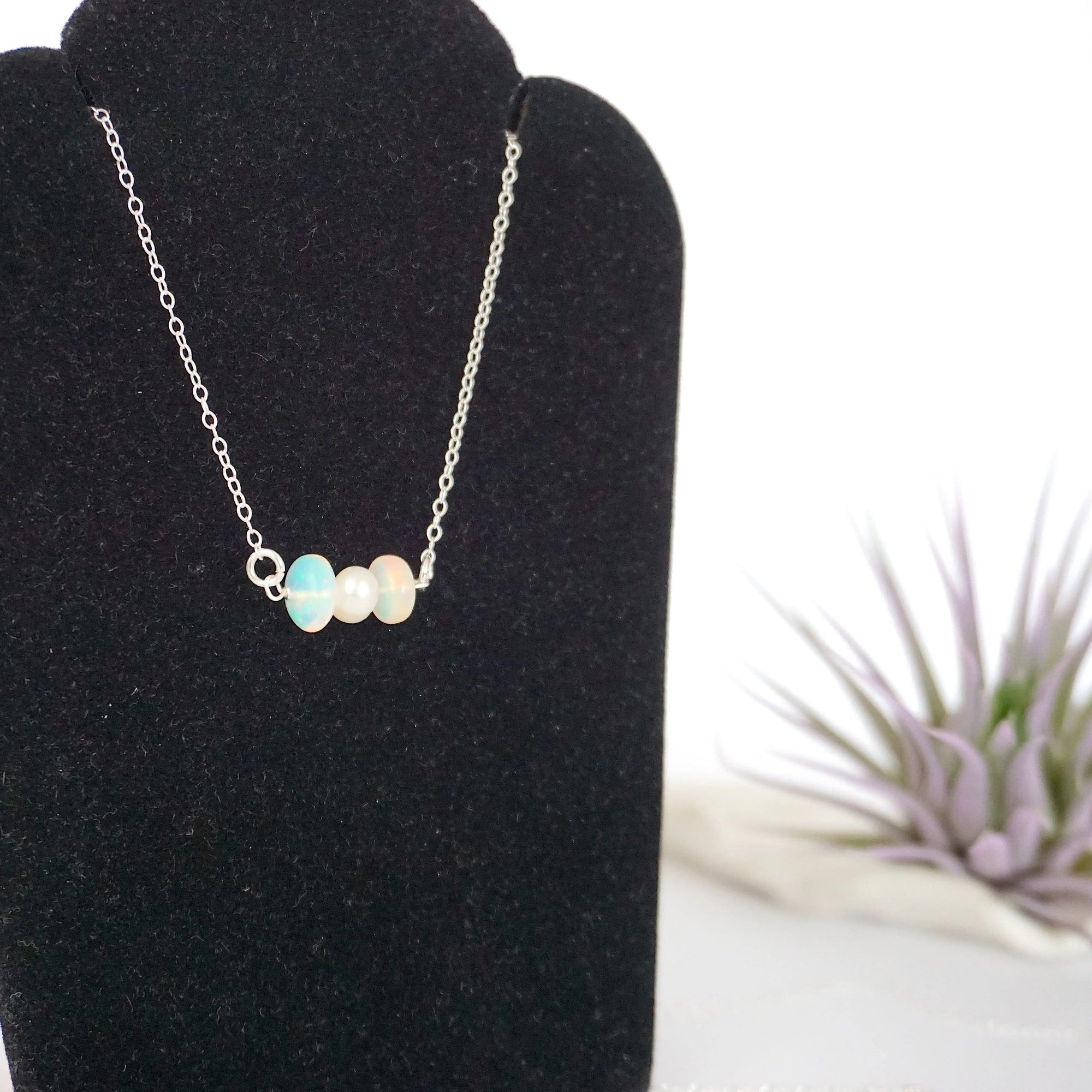 Focused left-side close-up of sterling silver opal and pearl bar necklace on jewelry display