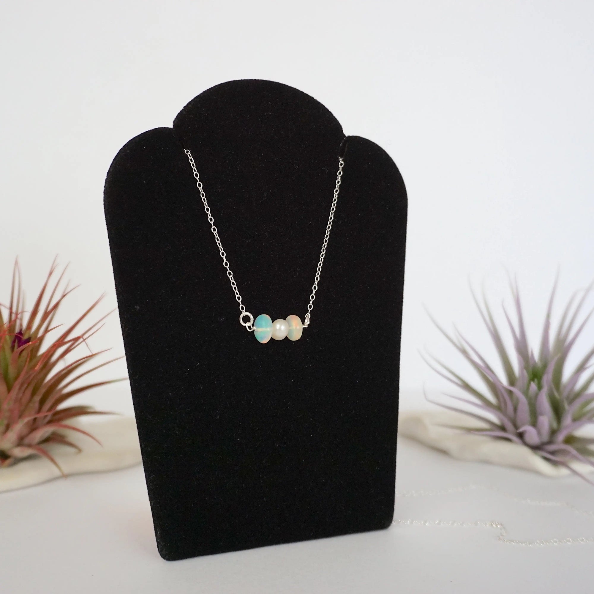 Right angle view of opal and freshwater pearl bar necklace in 925 sterling silver on jewelry display