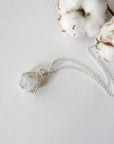 Sterling silver opal pendant on chain laying flat, handcrafted jewelry by Designs by Nature Gems.