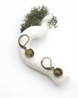 Bird’s eye view of peridot drop earrings laying flat on a display, showing detailed wire wrapping and gemstone color.