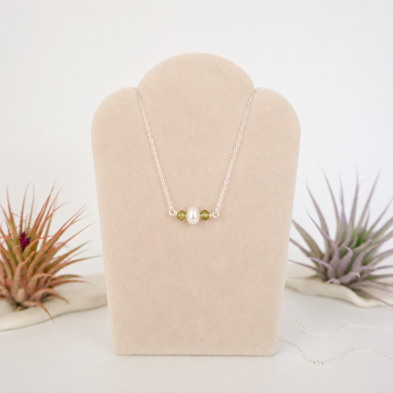 Peridot and freshwater pearl bar necklace in 925 sterling silver on jewelry display, front view