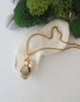Peridot and freshwater pearl pendant on gold plated brass chain laying flat, handmade wire wrapped jewelry for women